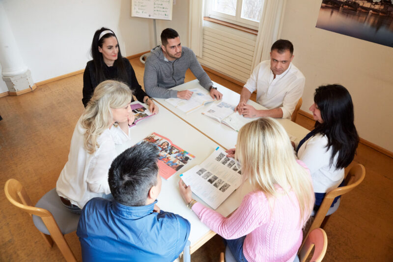 A class group works together on documents at a table in the classroom
